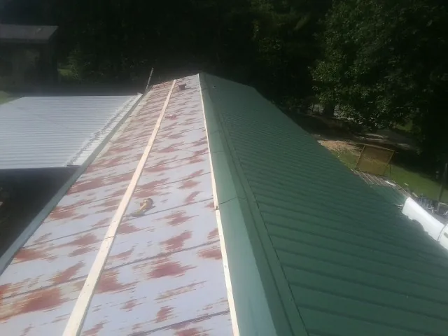 Old rusted panels beside newly installed green metal roofing — Wind Damage Roof Repair by Roofing Brothers in Thompsonville