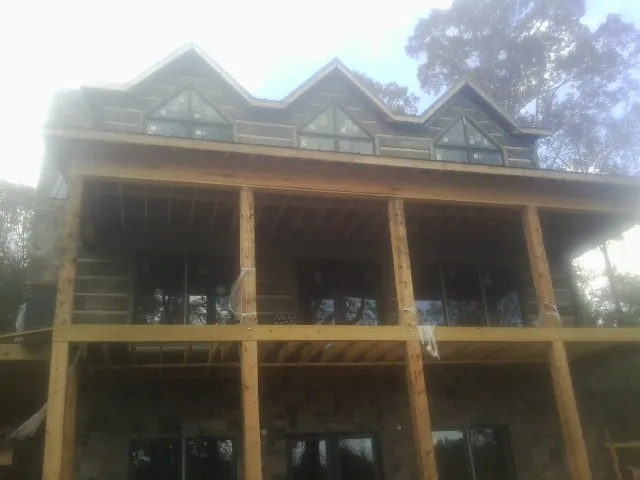 Dormers and porch framing on a large log home under construction — Roof Coating work by our crew in Thompsonville