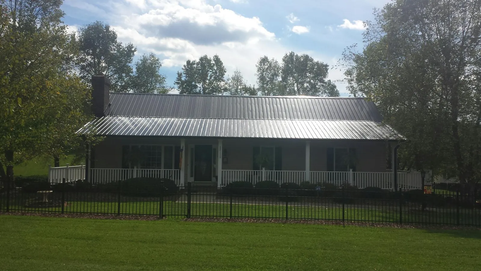 Gray metal roof on a brick ranch with a full width front porch — Gutter Guard Installation work by our crew in Thompsonville
