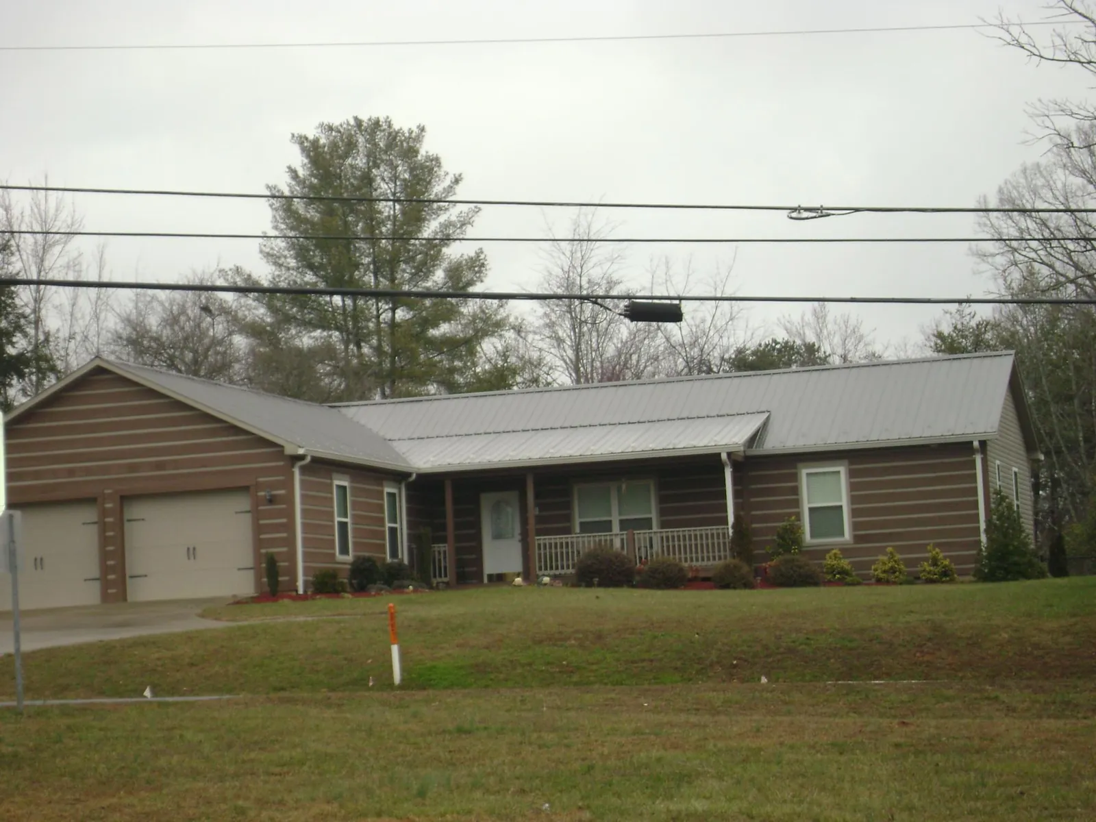 Gray metal roof on a log sided ranch home with a front porch in Thompsonville