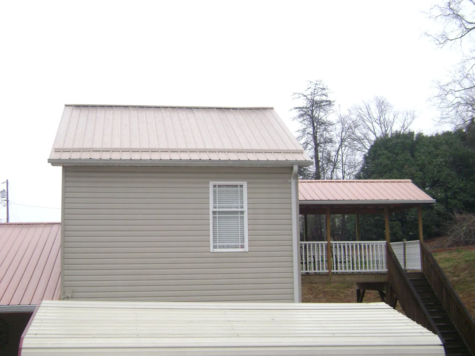 Tan metal roofs on a two story addition and attached porch, from a Roof Replacement job in Thompsonville