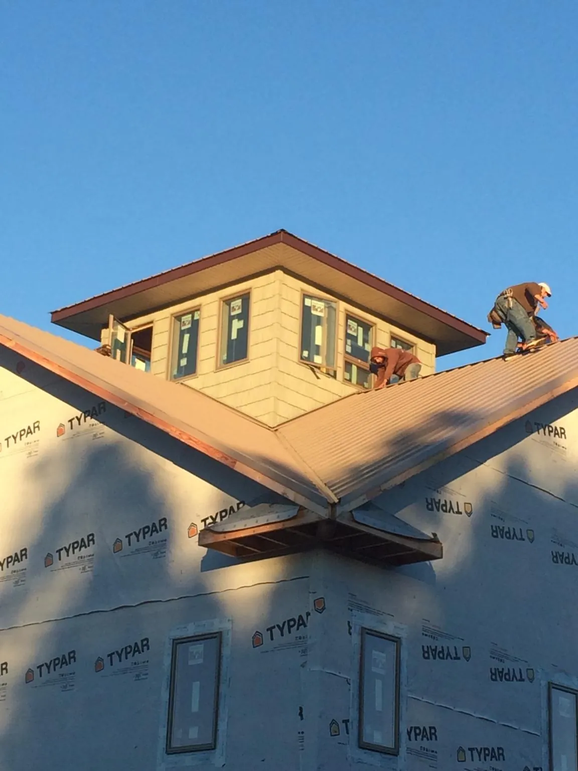 Roofers working around a rooftop cupola on a new metal roof at sunset — Roof Waterproofing in Thompsonville by Roofing Brothers